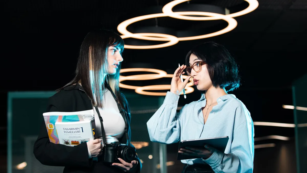 Two women in a modern office discussing with digital dev