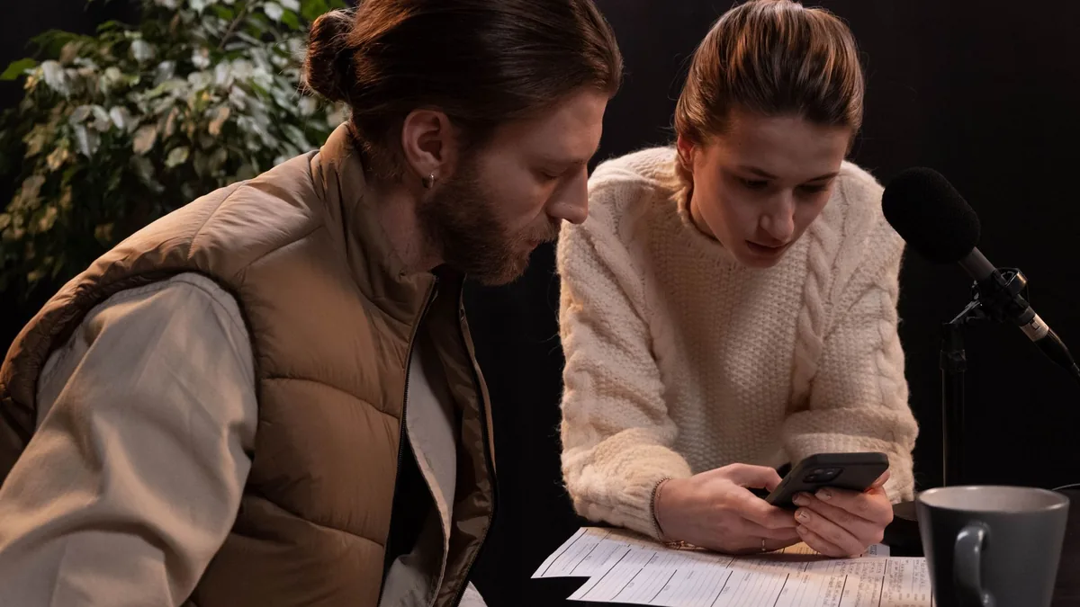 Two young adults engaged in podcast production using a s
