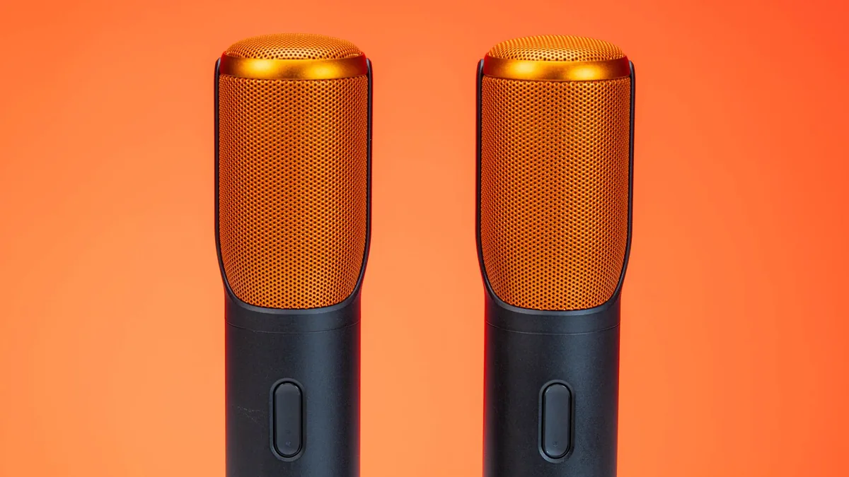 Vibrant photo of two modern microphones against an orang