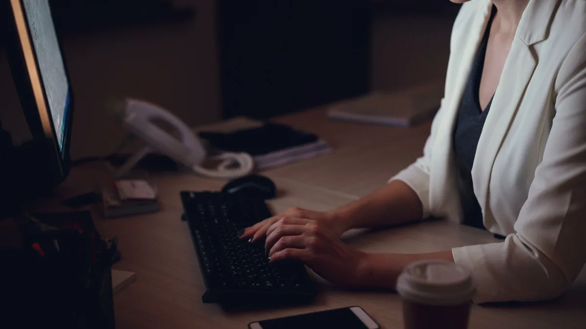 Woman in white blazer typing on keyboard late at night i