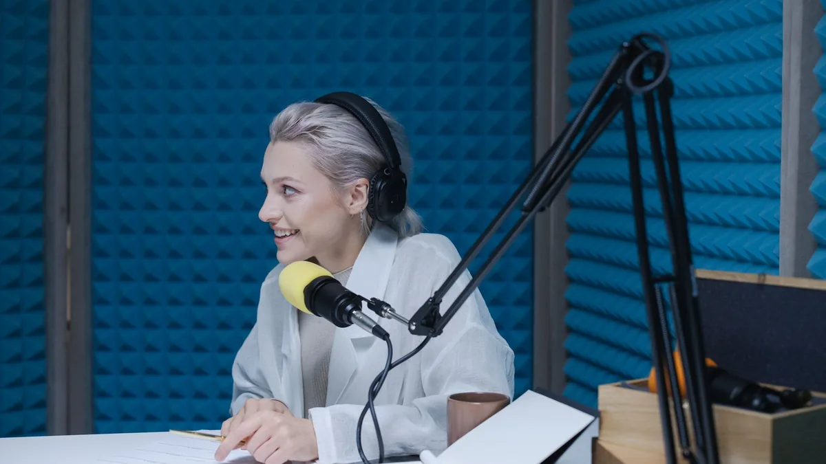 Woman wearing headphones recording a podcast in a soundp