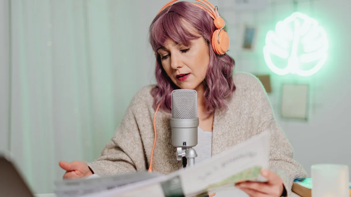 Woman with headphones podcasting indoors speaking into a