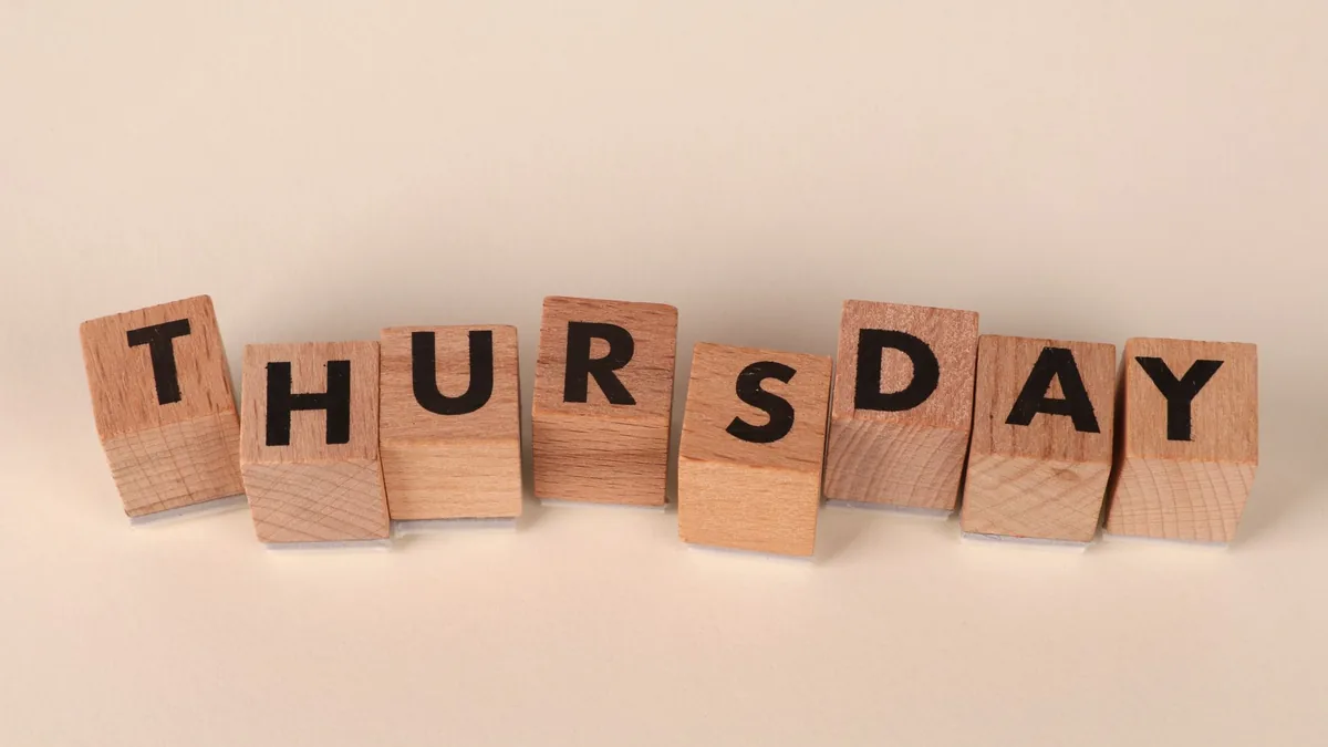 Wooden blocks arranged to spell thursday on a neutral ba