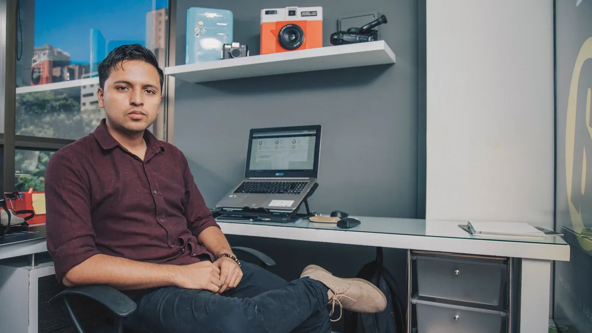 Young entrepreneur sitting at office desk with laptop an