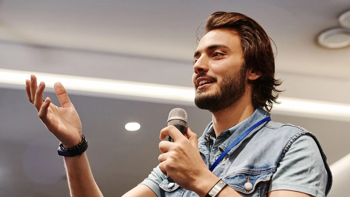 Young man with microphone speaking confidently at an ind