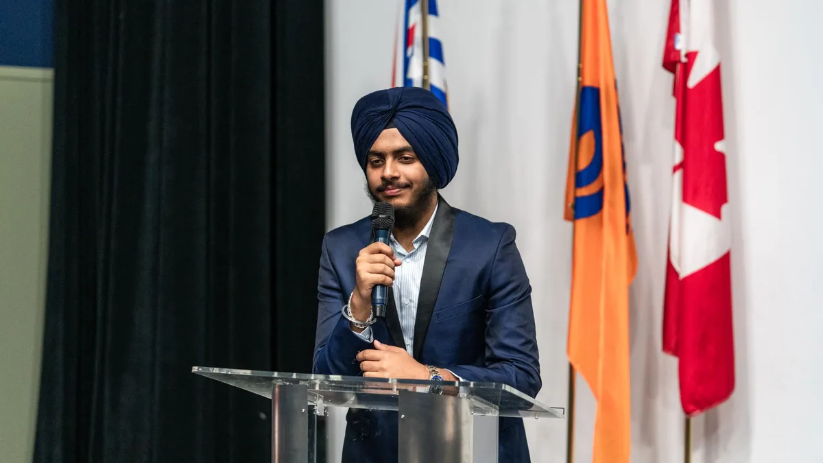 Young middle eastern man in turban speaking at a lectern