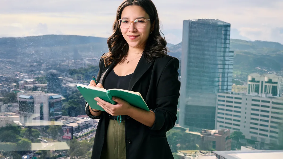 Young professional in glasses writing notes with urban c