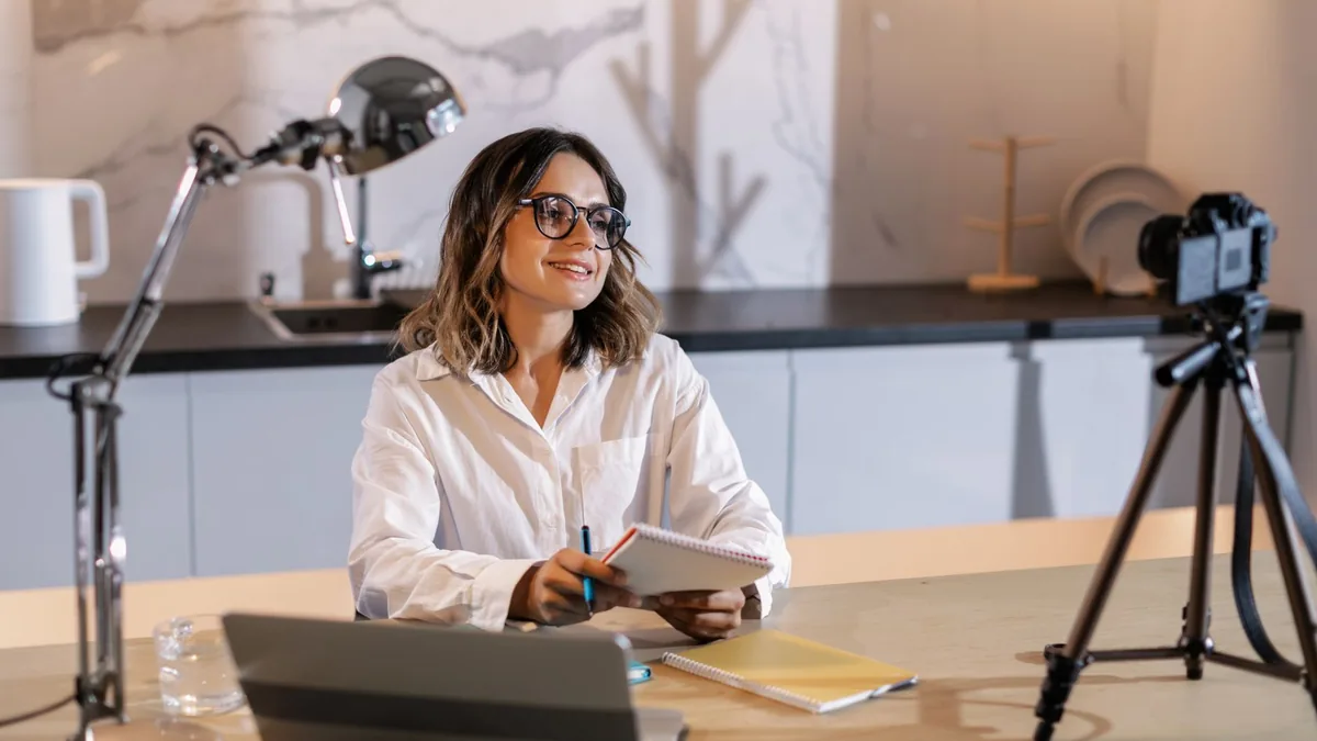 Young woman in glasses working indoors with laptop and c