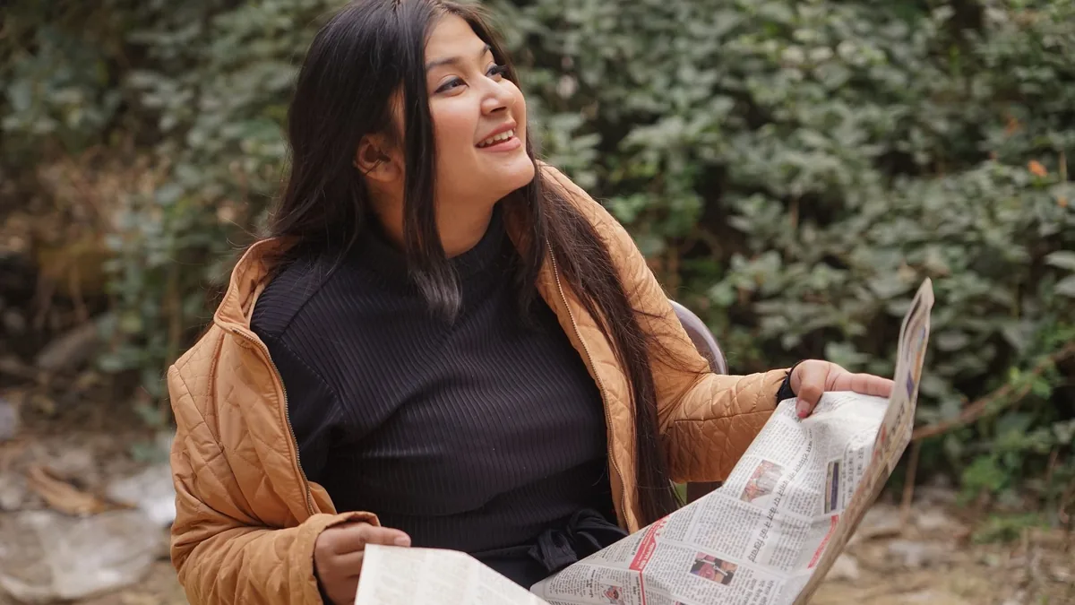 Young woman reading a newspaper outdoors in delhi enjoyi